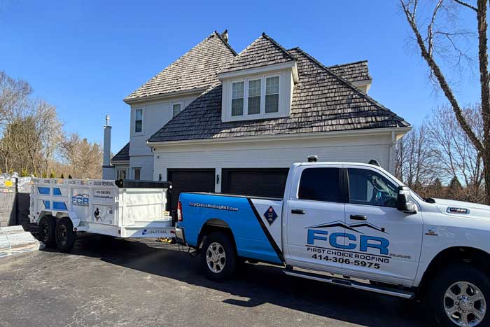 A professional service truck with a trailer at a customer roof replacement project near Elm Grove WI